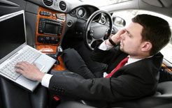 Driver sitting in car on the phone and using his laptop computer
