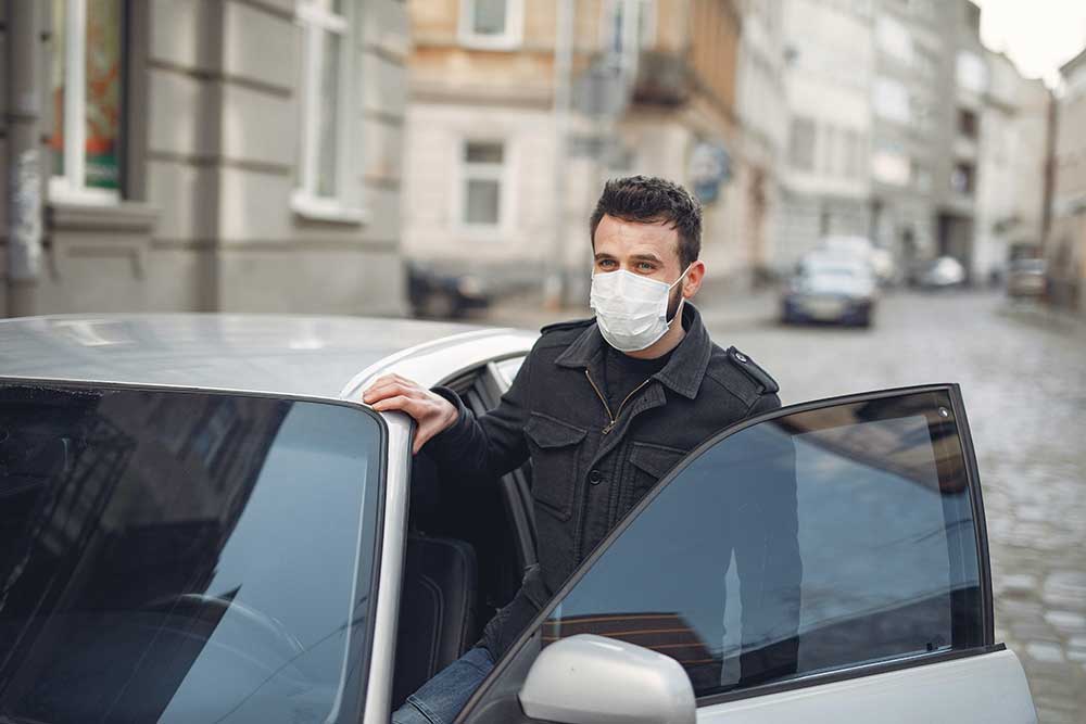 bearded man in medical mask getting out of car in street 3983438