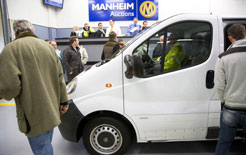 White delivery van on display at a motor show with visitors examining it.