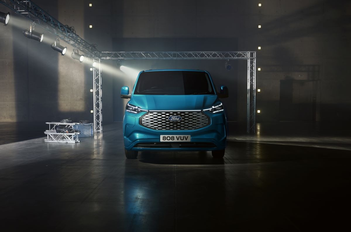 Blue Ford Transit electric van on display stage with professional lighting rig and metallic flooring