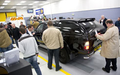 Visitors examining a black pickup truck at an indoor commercial vehicle exhibition or showroom.