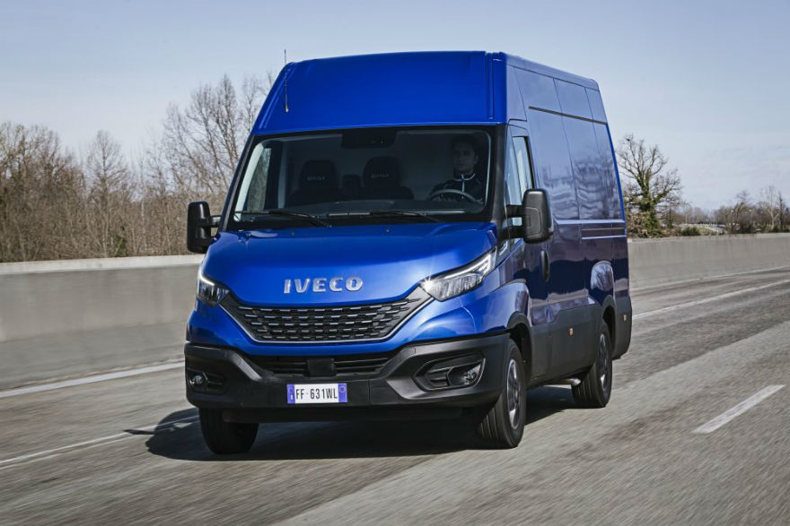 Blue Iveco van driving on motorway with bare trees in background