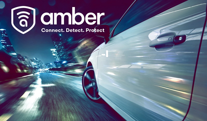 Silver car driving at speed on night-time motorway with Amber vehicle tracking device visible on door handle and Connect.…