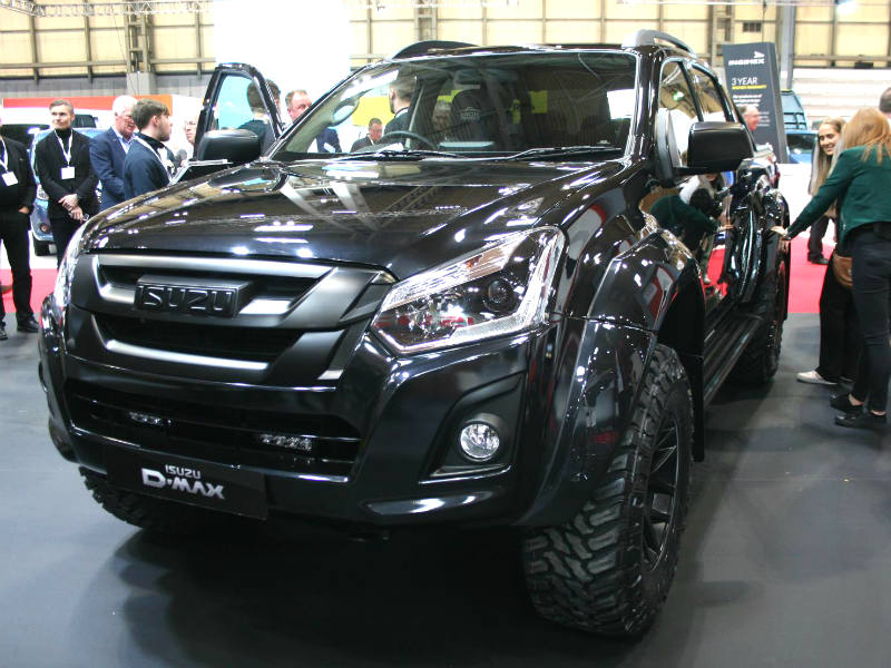 Black Isuzu D-Max pick-up truck on display at motor show with visitors viewing the vehicle.