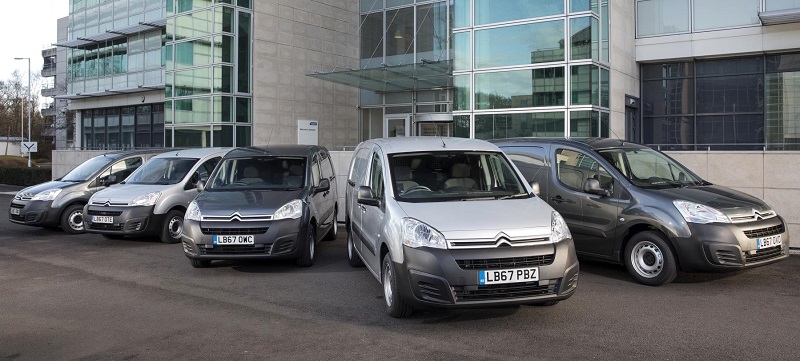 Fleet of five Citroën vans parked in front of modern office building, including white C1 and grey commercial vehicles.