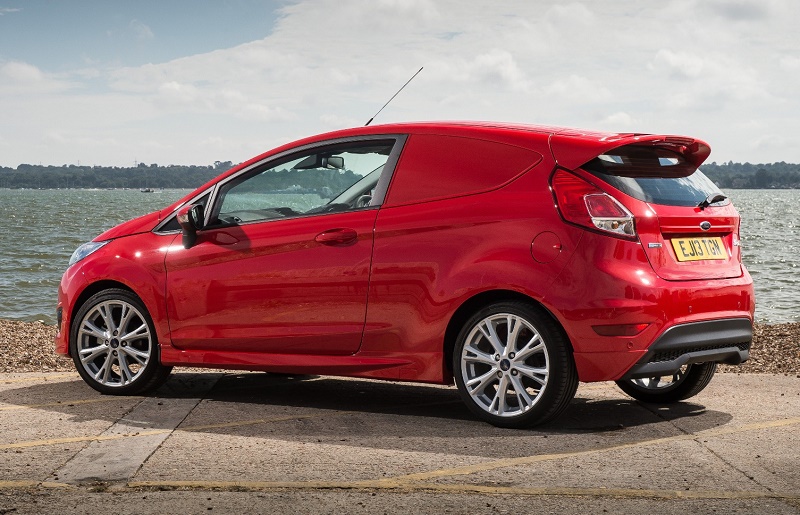 Red Ford Fiesta parked on shingle beach with sea and sky behind