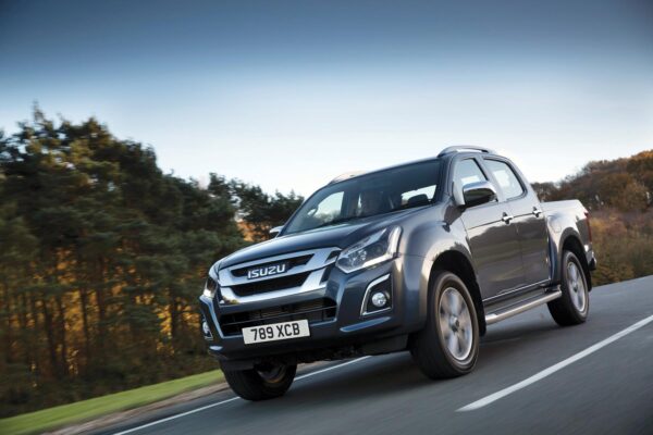 Silver Isuzu D-Max Blade driving on a dual carriageway with autumn woodland in the background.