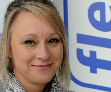 Woman with blonde hair smiling at camera, with blue Fleet Assist logo visible behind her.