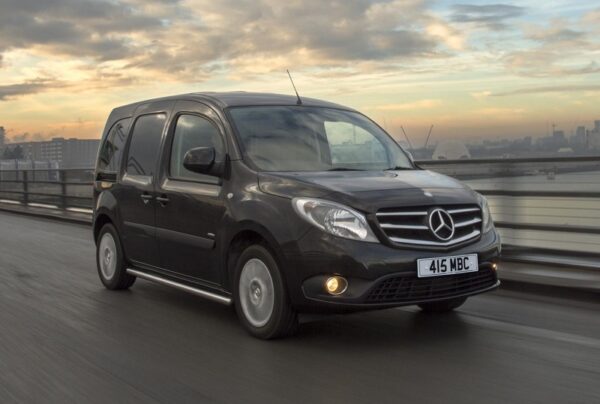 Black Mercedes-Benz Citan van on riverside road with dawn sky and London skyline behind.