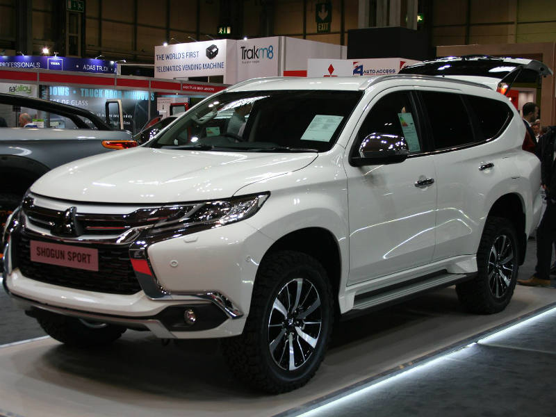 White Mitsubishi Shogun Sport Commercial on display at CV Show, side view with sponsor boards visible in background.