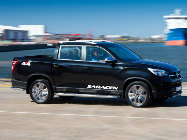 Black SsangYong Musso pickup truck with Saracen badging parked at dockside with cargo ship in background.