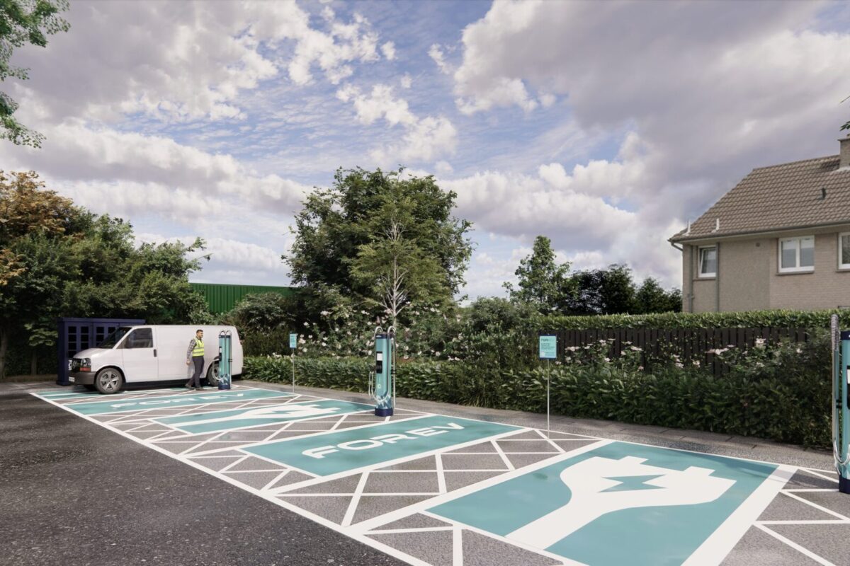 Electric vehicle charging bay with turquoise markings and white lines in residential area, white van parked beside…