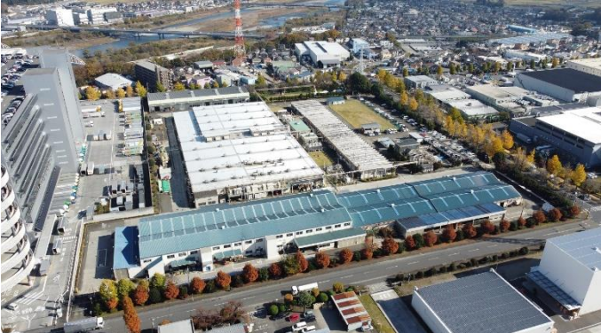 Aerial view of Mitsubishi Fuso manufacturing facility with solar panels on roof and industrial buildings surrounded by…