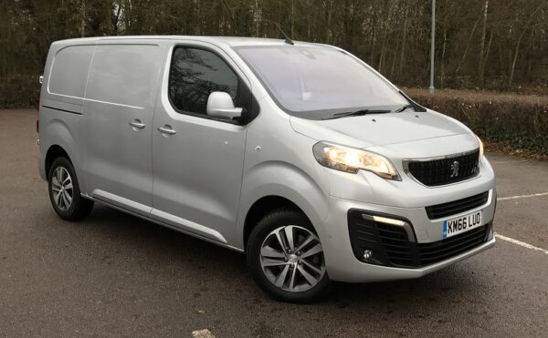 White Peugeot Expert Professional Plus van parked on tarmac, front three-quarter view showing grille and alloy wheels.
