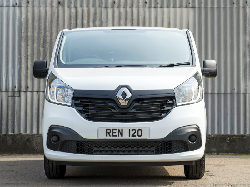 White Renault Trafic van with registration plate REN 120, photographed head-on against corrugated metal backdrop.