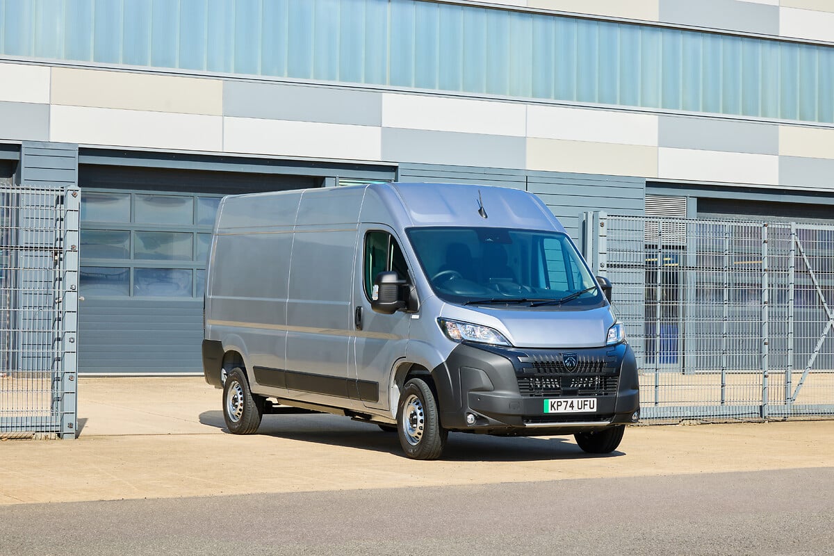 Silver Citroën e-Dispatch van parked outside industrial building with metal fencing.