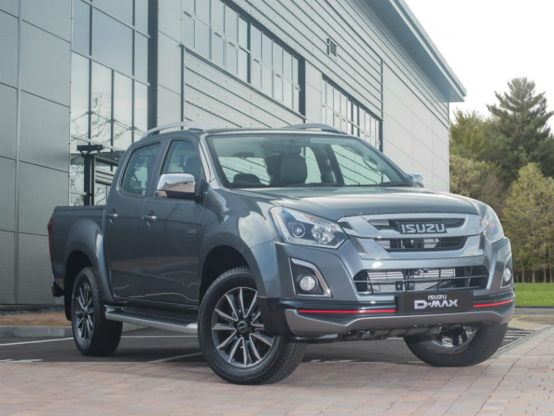 Isuzu D-Max Utah V-Cross double cab in metallic grey parked outside modern building with landscaping.