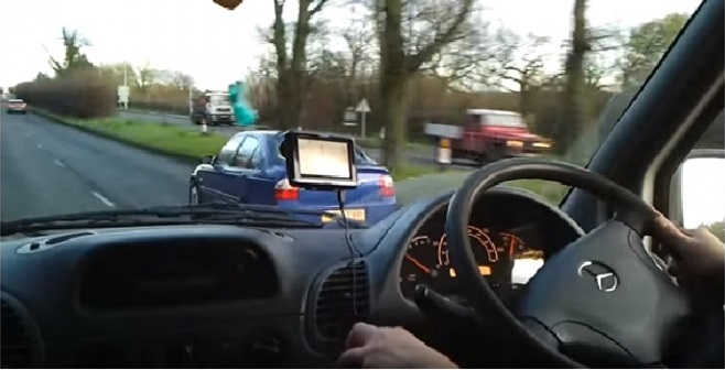 View from van driver's seat of dashboard and road ahead, with sat nav mounted on windscreen and other vehicles visible in…