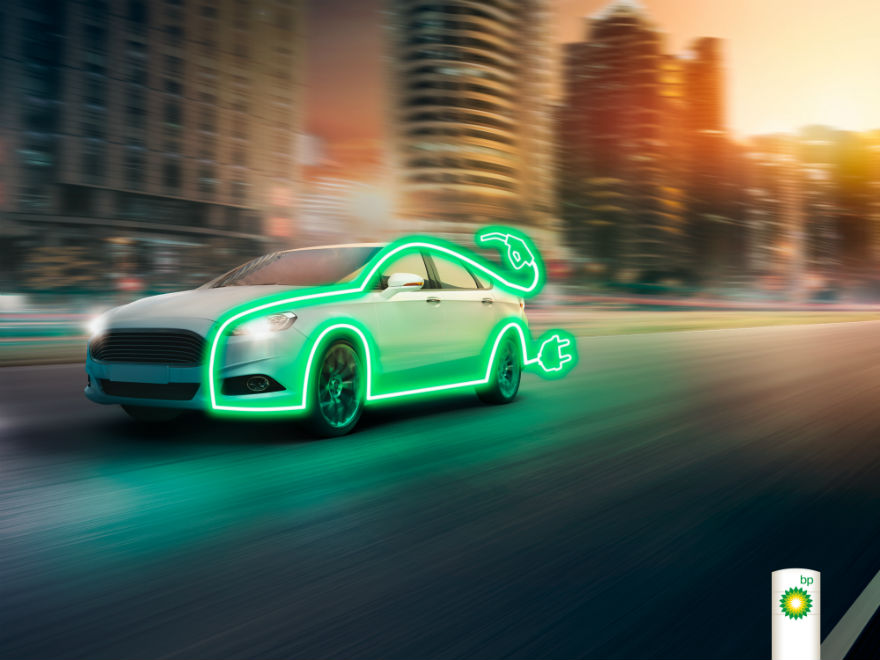 Electric vehicle outlined in bright green neon on city street at sunset, with charging plug symbol and BP logo.
