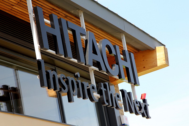 Hitachi Inspection and Hitachi signage on modern building exterior with wooden overhang and metal lettering.