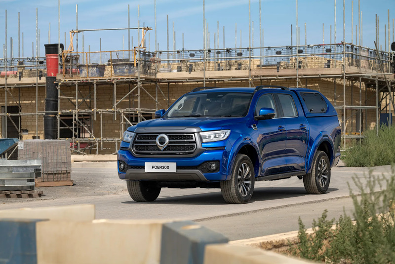 Blue GWM POER300 pickup truck parked on construction site with scaffolding and stone blocks in background.