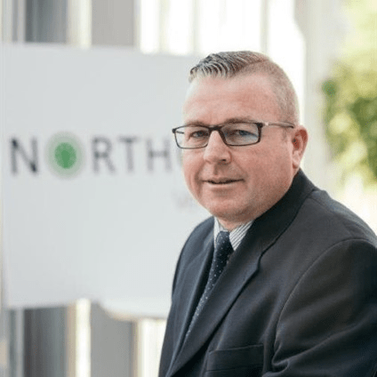 Adam Naylor, UK Head of Sales at Northgate Vehicle Hire, wearing glasses and dark suit jacket against company signage.