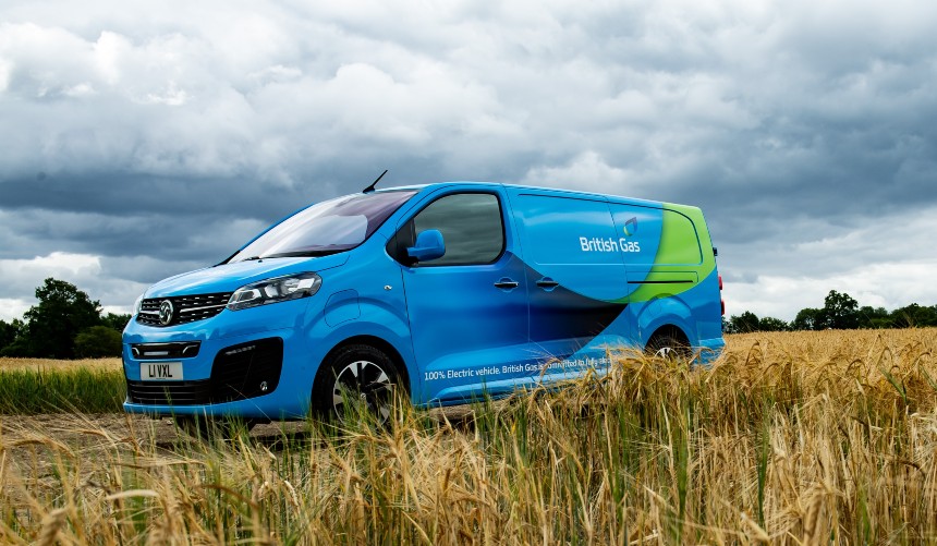 Blue and lime electric van parked in a wheat field under cloudy sky, branded with British Gas livery.