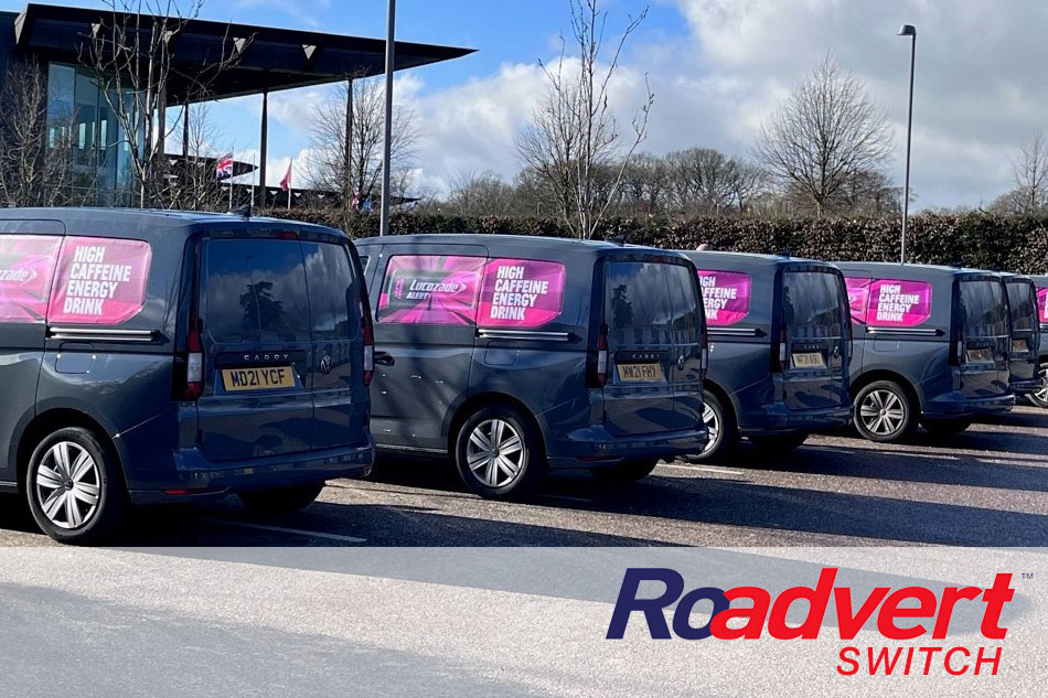 Row of blue vans parked in line with bright pink removable graphics on their sides advertising Roadvert Switch.