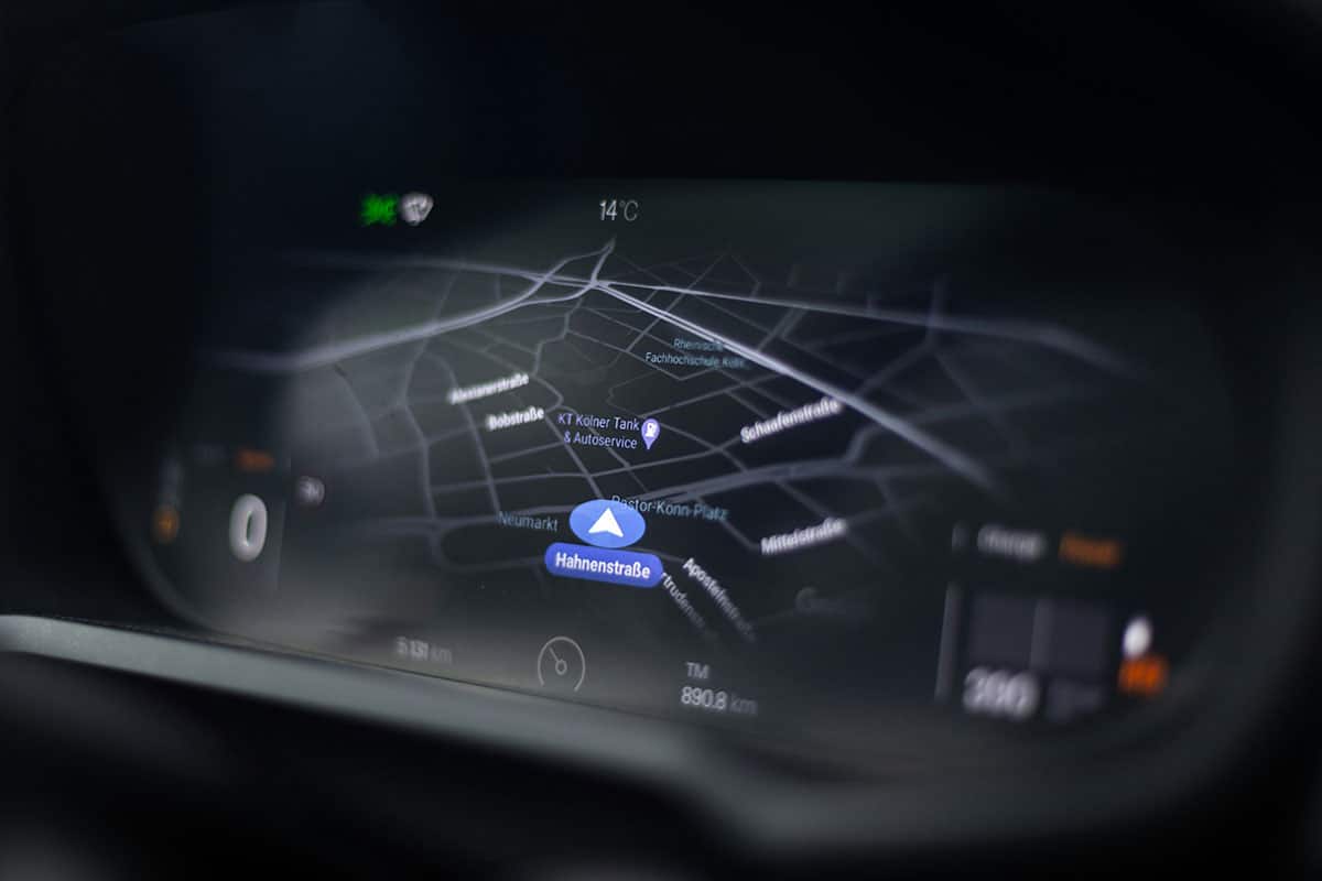 Car dashboard displaying GPS navigation map with route optimization and street directions highlighted in blue.