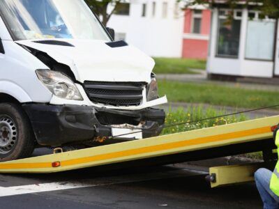Wrecked white car pulling into tow truck