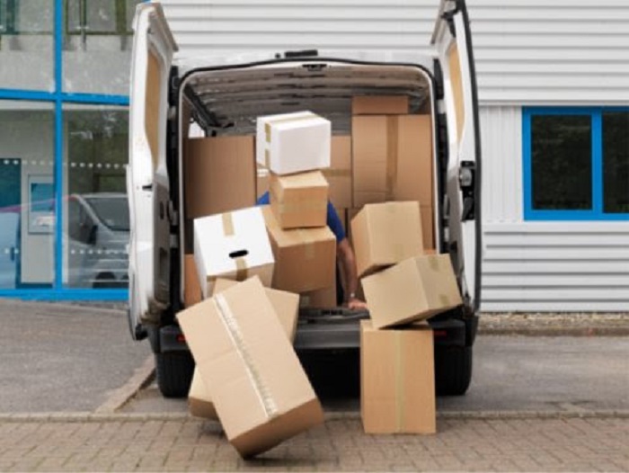 White delivery van loaded with cardboard boxes, some falling out of open rear doors.