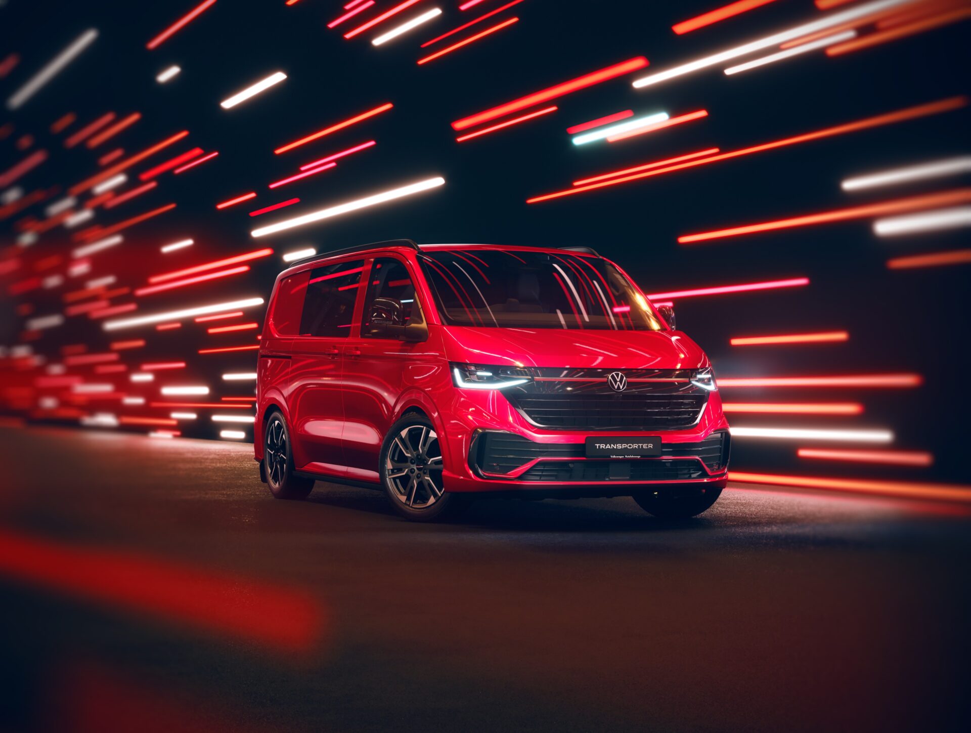 Red Volkswagen Transporter van against abstract red and white light streaks on dark background.