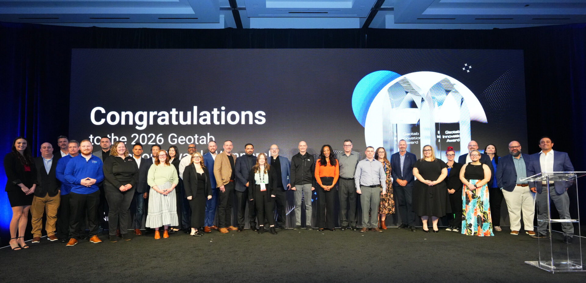 Group of people standing on stage in front of large screen displaying "Congratulations HATS 2026 Geotab" with globe graphic.
