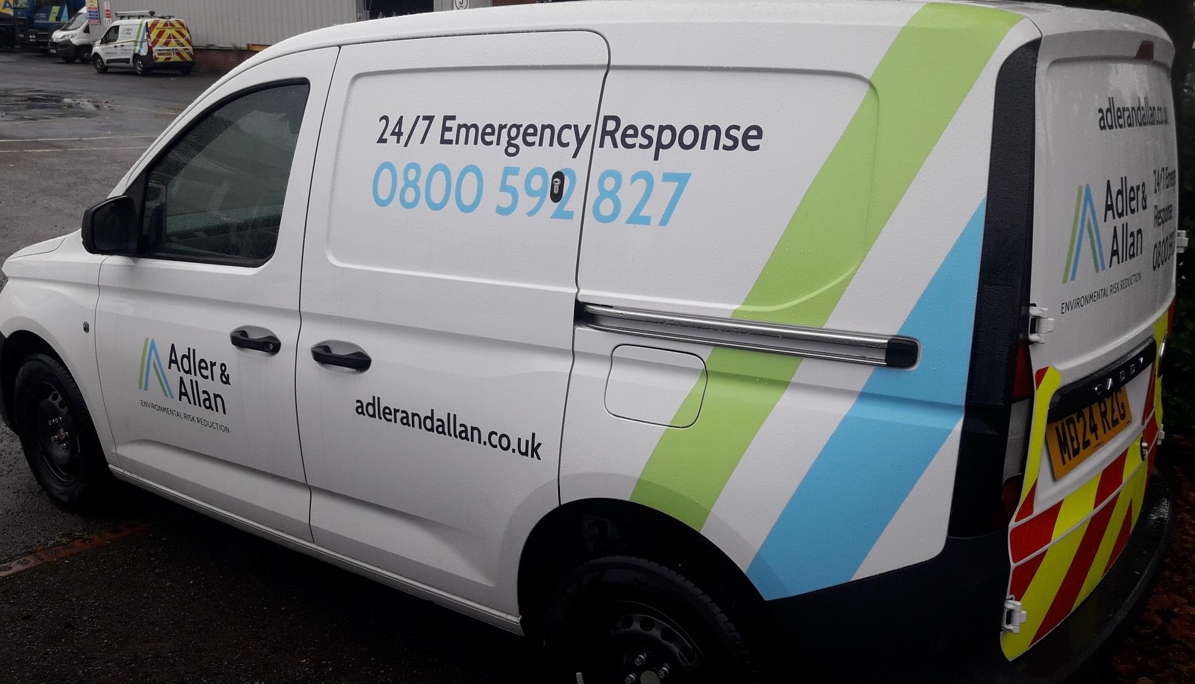 White Adler & Allan emergency response van with lime green and blue stripe branding, displaying 24/7 contact number and…