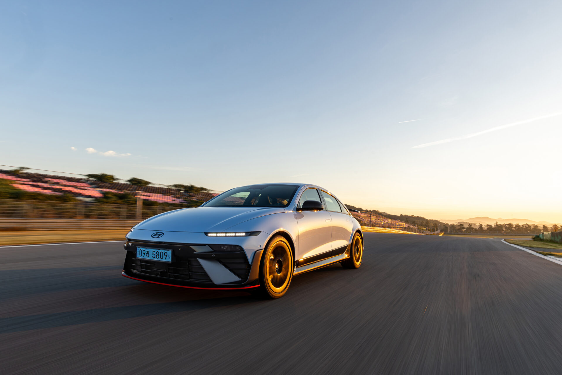 Silver Hyundai IONIQ 6 N with orange accents driving on a motorway at dusk.