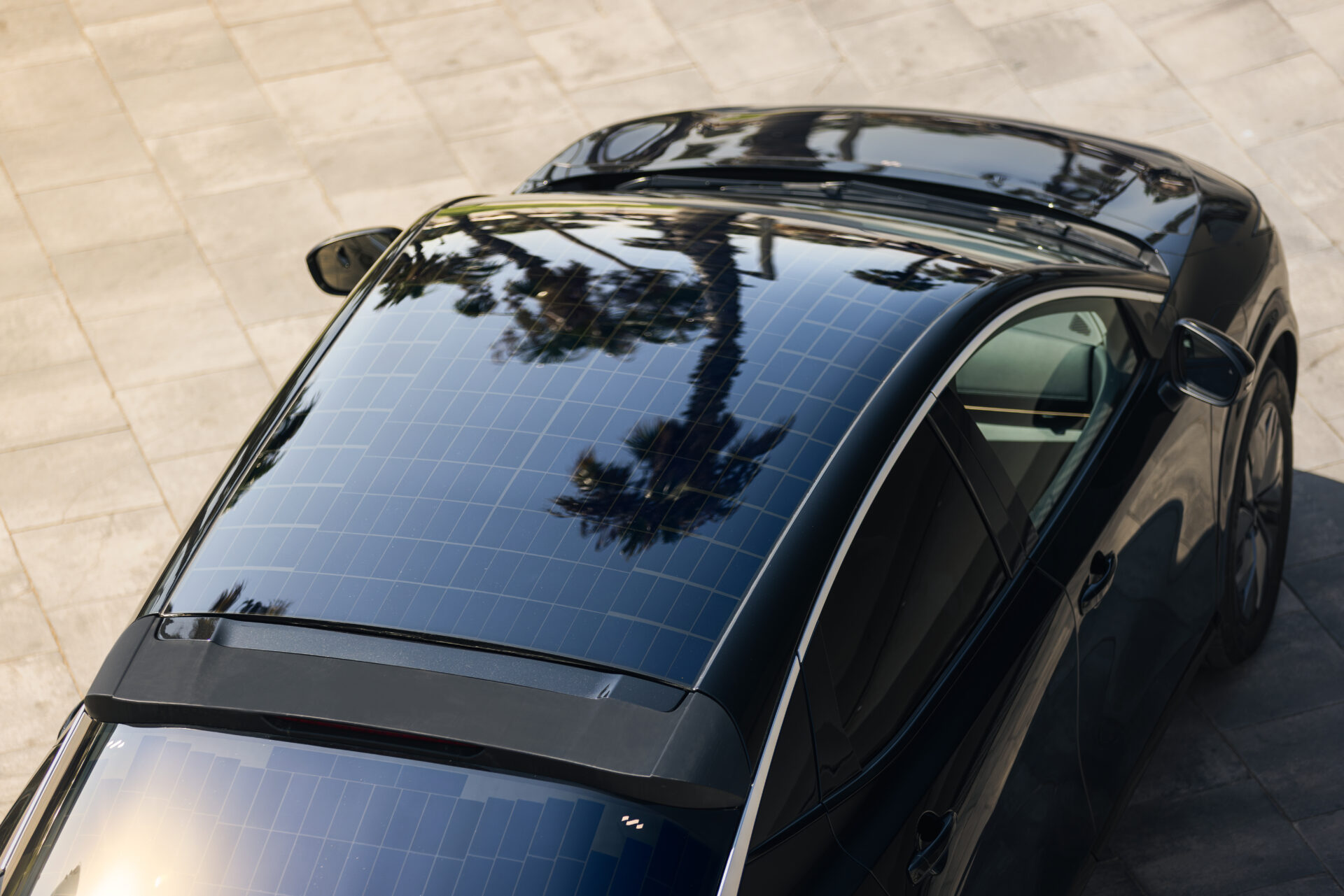 Black Nissan electric vehicle with integrated solar panels on roof, viewed from above in daylight.