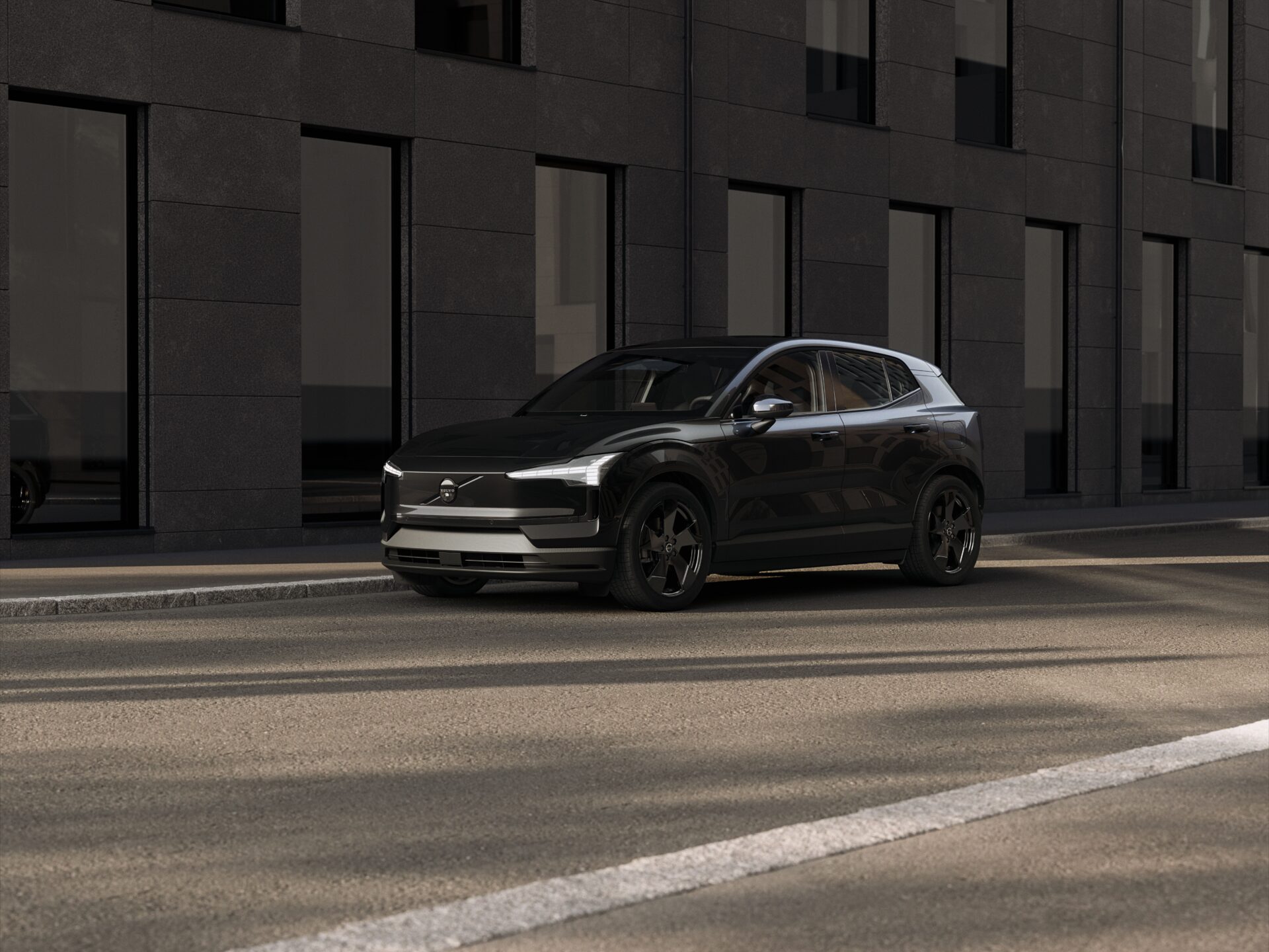 Black Volvo EX30 parked outside modern building with dark facade.