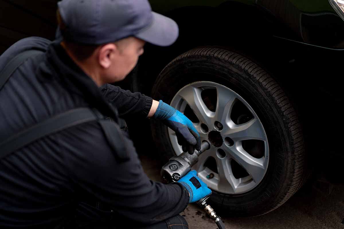 auto-mechanic-in-changing-a-wheel-from-black-car-u-2024-11-26-10-21-39-utc