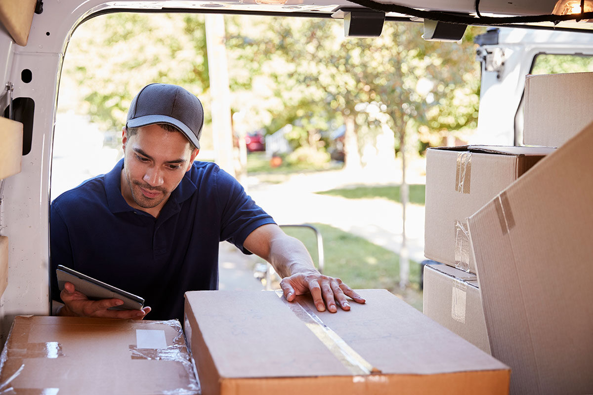courier-with-digital-tablet-checking-packages-in-v-PV8PXL3